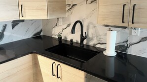 A kitchen with light wood cabinets, black countertops, and a black sink. - Chic Basement Suite ATL - Private Entrance & Free Charge and Park (Atlanta)
