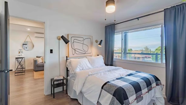 A modern bedroom with a large bed, a view of the outdoors, and a minimalist decor. - INN ON THE BENCH (Lincoln)