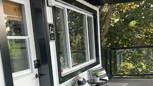 A covered outdoor area with a door, windows, a potted plant, a bench, and a doormat. - INN ON THE BENCH (Lincoln)