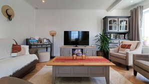 A living room with a TV, sofa, armchair, coffee table, and a cabinet with glass doors. - 5 bedroom beautiful home in Westende (Westende)