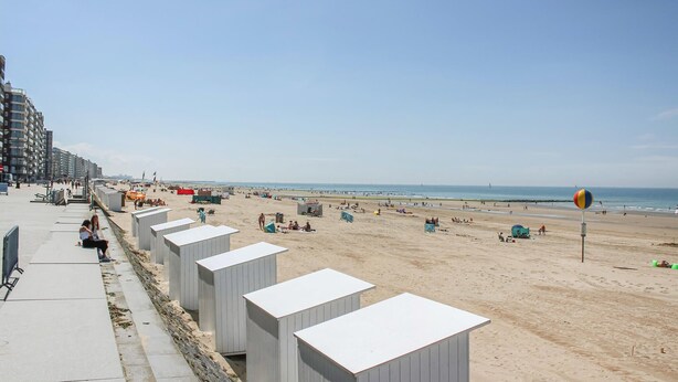 A beach with rows of white beach huts along the promenade, a clear sky, and the ocean in the background. - 5 bedroom beautiful home in Westende (Westende)