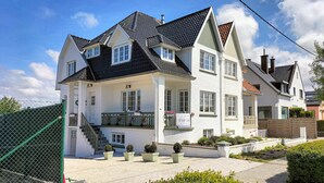 A two-story house with a steeply pitched roof, multiple windows, and a front porch with a staircase. - 5 bedroom beautiful home in Westende (Westende)