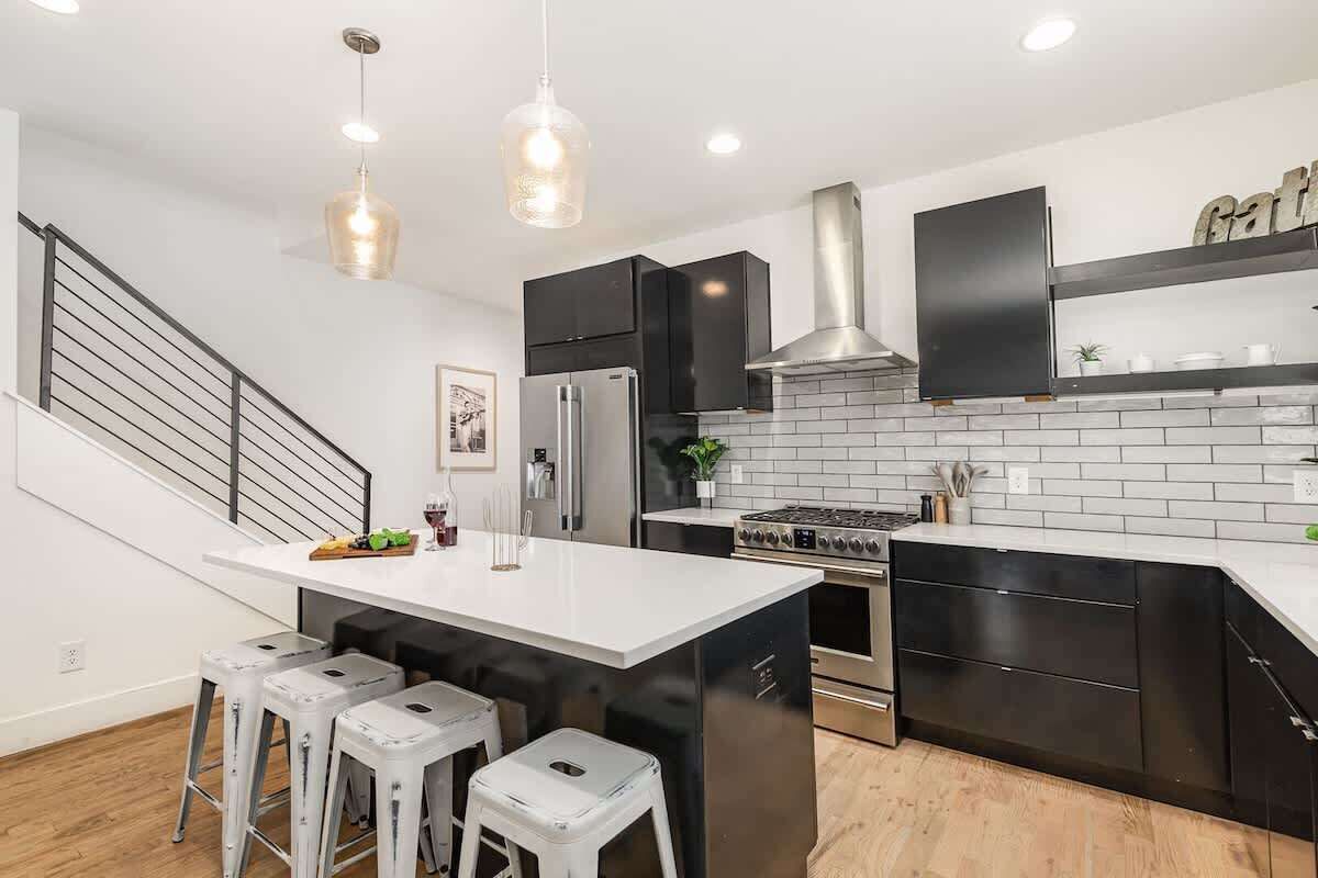 A modern kitchen with a central island, stainless steel appliances, and black cabinetry.