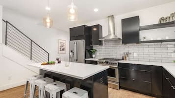 A modern kitchen with a central island, stainless steel appliances, and black cabinetry.