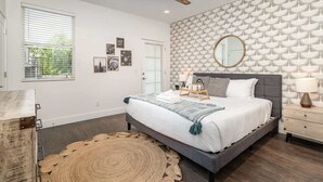 Ein Schlafzimmer mit einem Bett, einem Deckenventilator, einer Wand mit Muster und einem Fenster mit Jalousien.