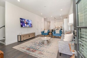A modern living room with a flat-screen TV, sofas, a coffee table, and a patterned rug. - Double Time - Ping-Pong Table - Mins to Germantown (Nashville)