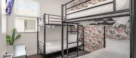 A bunk bed room with a ceiling fan, a window with blinds, and a plant.