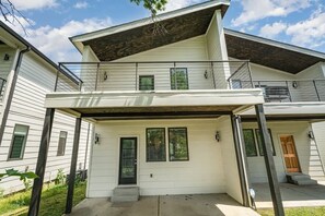 Une maison à deux étages avec un porche abrité, une porte d’entrée et un petit escalier menant à l’entrée.