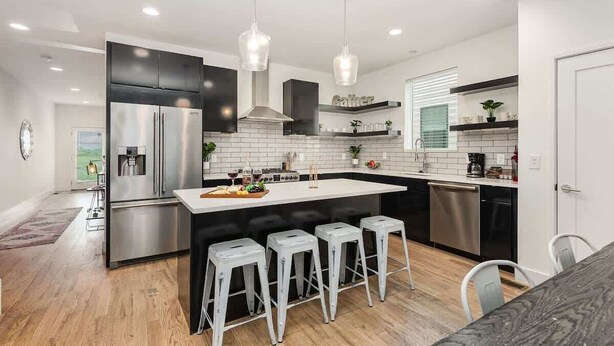 A modern kitchen with a central island, stainless steel appliances, and bar stools.