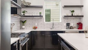 A modern kitchen with a central island, built-in appliances, and decorative plants.