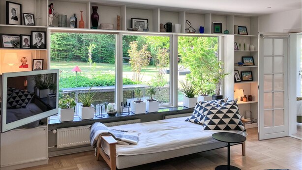A modern bedroom with a bed, a TV, and a large window overlooking a garden. - 3 bedroom nice home in Birkerød (Birkerød)