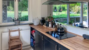 A kitchen with a wooden countertop, black cabinets, a glass hood, and a view of a garden through large windows. - 3 bedroom nice home in Birkerød (Birkerød)