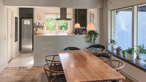 A modern kitchen with a central island, pendant lights, and a view of greenery outside. - 3 bedroom nice home in Birkerød (Birkerød)