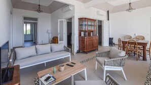A spacious living room with a sofa, a coffee table, and a dining area with chairs and a table. There is a wooden cabinet with glass doors and an air conditioning unit on the wall. - 5 bedroom nice home in Bovalino (Bovalino)