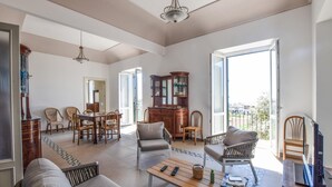 A spacious living room with a dining area, a large wooden cabinet, and a view of the outside. - 5 bedroom nice home in Bovalino (Bovalino)