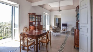 A spacious living area with a wooden dining table, chairs, a sofa, and a TV. - 5 bedroom nice home in Bovalino (Bovalino)