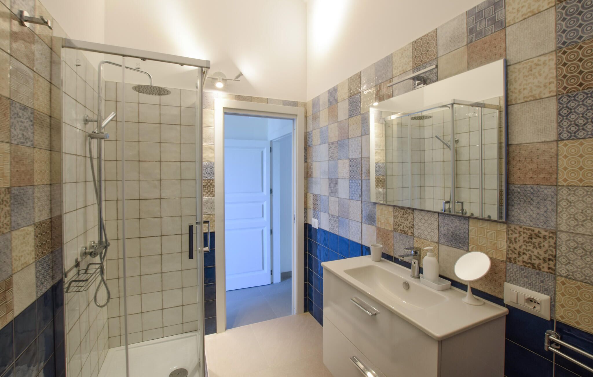 Un baño con ducha, lavamanos y espejo.