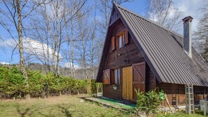 Une cabane en bois avec un toit à forte pente, une grande fenêtre et une cheminée.