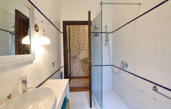 Une salle de bain avec une baignoire blanche, une cabine de douche en verre et un miroir doté d’un cadre à motifs.