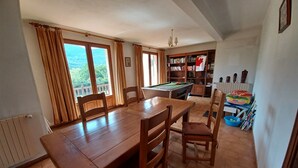 Un comedor con una mesa y sillas de madera, una mesa de billar y una estantería llena de libros.