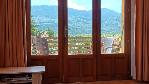 Una habitación con puerta de madera que da a un balcón con vistas a la montaña.