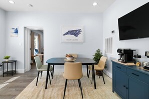 Et moderne spiseområde med et sort bord, beige stole og et indrammet kort over North Carolina på væggen.