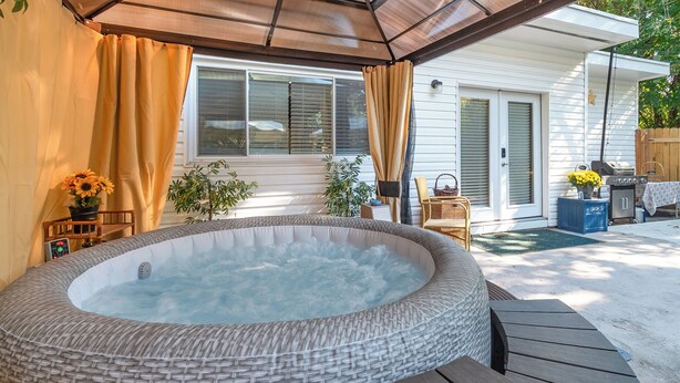 Un jacuzzi en un espacio exterior cubierto, con un muelle de madera, un ventanal y una puerta.
