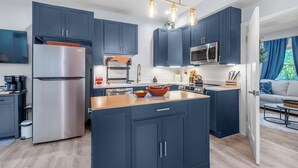 Una cocina moderna con armarios azul oscuro, electrodomésticos de acero inoxidable y una isla de madera.