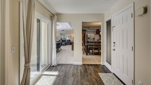 Un pasillo con piso de madera, paredes blancas y una puerta que da a una cocina.