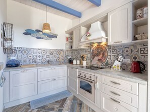 Een koelkast, een oven, een vaatwasser, kookgerei, borden en bestek