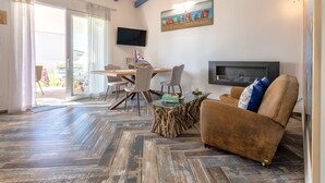 A spacious living area with a wooden herringbone floor, a brown leather sofa, a glass coffee table, and a dining table with chairs. - Le Rêve by Interhome (Valledoria)