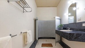 Une salle de bain avec un lavabo blanc, un miroir, un porte-serviettes et un espace douche.