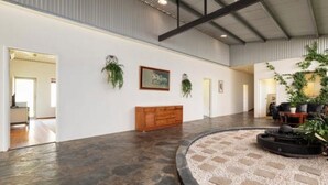 Un hall d’entrée spacieux doté d’un sol en pierre, d’un banc en bois et d’un espace de détente circulaire agrémenté de plantes.