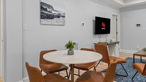 A modern room with a round table, brown leather chairs, a TV, and a framed picture on the wall.