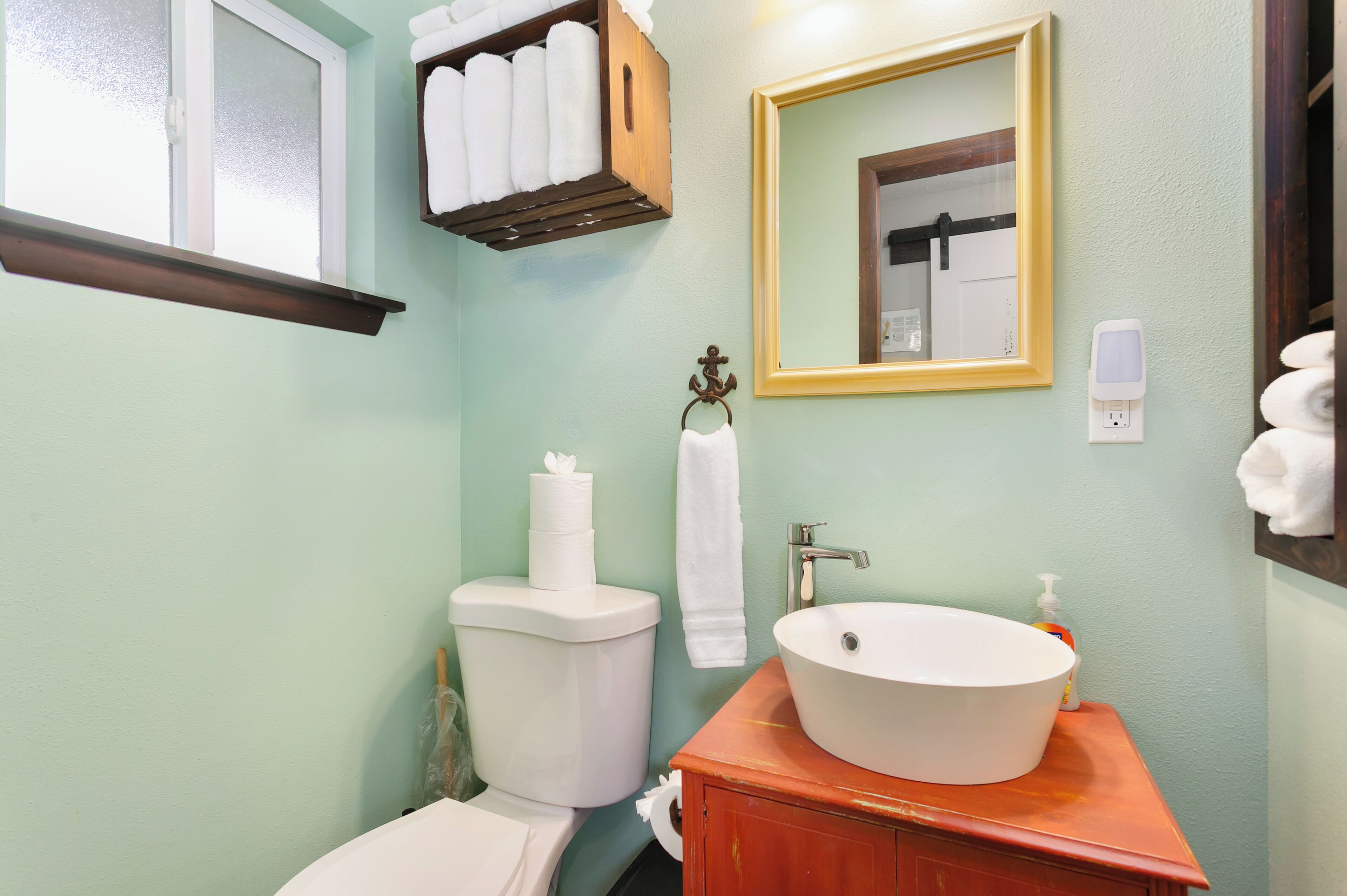 A bathroom with a toilet, sink, mirror, and towel rack.