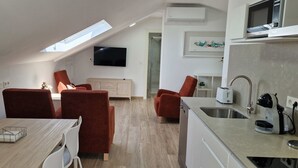 Un espacio habitable compacto con comedor, cocina y televisor montado en la pared.