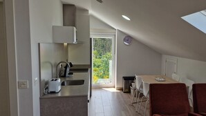 Una cocina moderna con horno empotrado, pileta y tostadora. Hay una zona de comedor con mesa y sillas, y un tragaluz arriba.