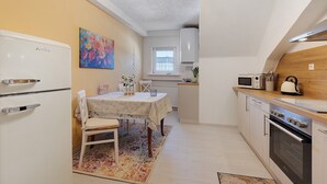 A compact kitchen with a refrigerator, stove, microwave, and a dining area with a table and chairs. - Holiday Apartment 'Fleur' with Wi-Fi (Tengen)