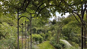 A garden pathway with a metal archway, surrounded by lush greenery and various plants. - Holiday Apartment 'Fleur' with Wi-Fi (Tengen)