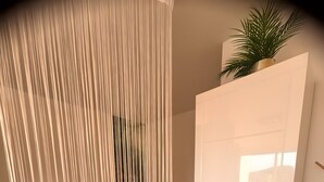 A room with a bed, a white wardrobe, and a plant on top.