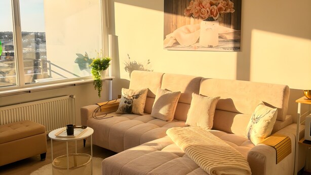 A modern living room with a sofa set, a round coffee table, a side table, and a large window with a view.