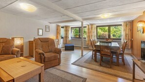 A spacious living area with a dining table, two sofas, and a television. - Apartment 'Demberg' with Mountain View, Private Terrace and Wi-Fi (Schmallenberg)