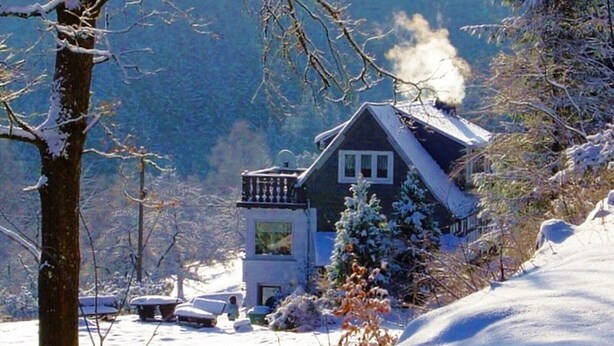 A house with a balcony, surrounded by snow-covered trees and a mountain in the background. - Apartment 'Demberg' with Mountain View, Private Terrace and Wi-Fi (Schmallenberg)
