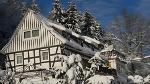 A traditional half-timbered house with snow-covered trees and a clear sky. - Apartment 'Demberg' with Mountain View, Private Terrace and Wi-Fi (Schmallenberg)
