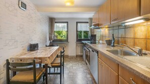 A compact kitchen with a coffee machine, a sink, and a window with curtains. - Apartment 'Demberg' with Mountain View, Private Terrace and Wi-Fi (Schmallenberg)