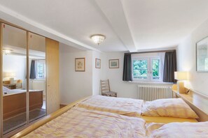 Ein Schlafzimmer mit Bett, Stuhl, Fenster und Heizkörper.