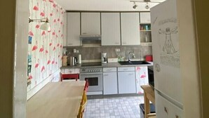 A kitchen with white cabinets, a tiled floor, and a dining area with chairs and a table.