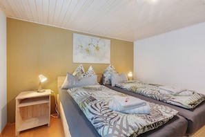 Un dormitorio con dos camas, una mesita de noche, una lámpara y una obra de arte colgada en la pared.