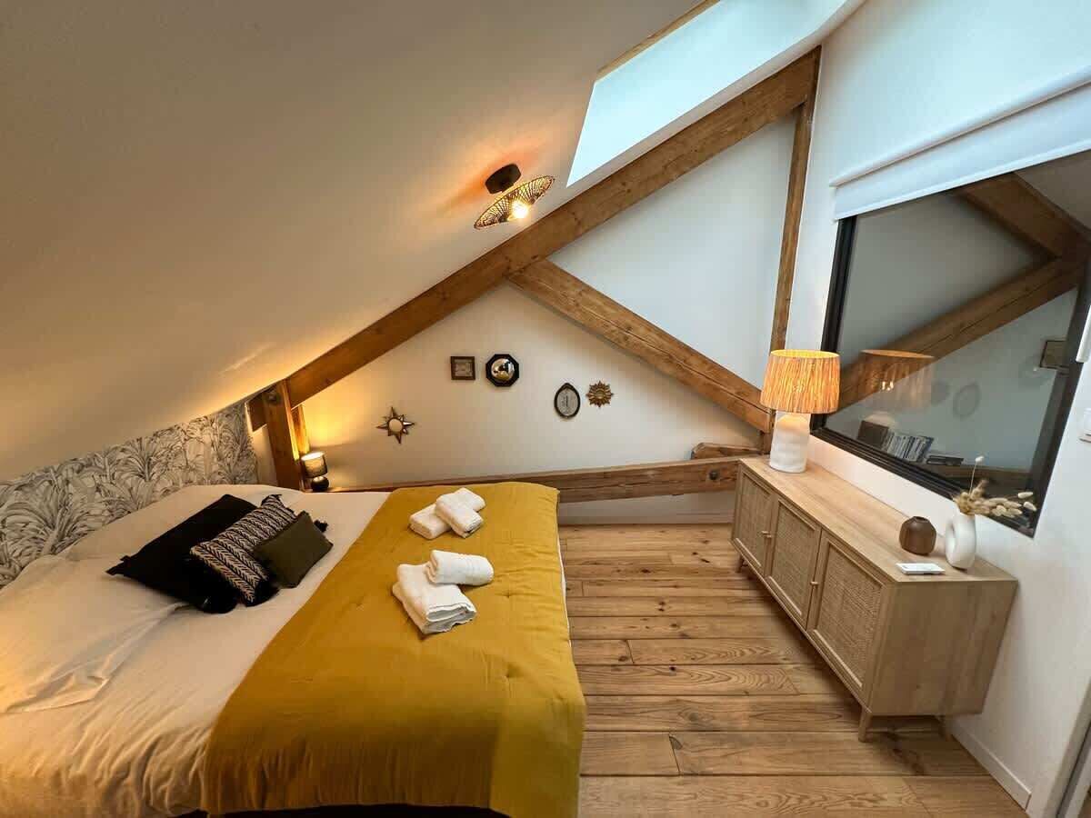 A bedroom with a bed, a bedside table, a lamp, and a window.