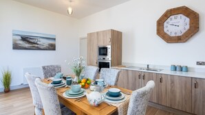 A modern kitchen with wooden cabinets, a built-in oven, and a clock on the wall. - Great Glen View by Interhome (Inverness)